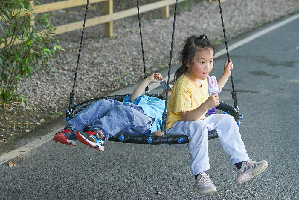 Girl playing on platform nest swing at commercial playground - durable play area attraction